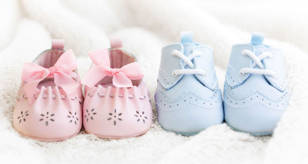 Two pairs of baby shoes, one pink with flower cutouts and a bow, the other blue with lace-up detailing.