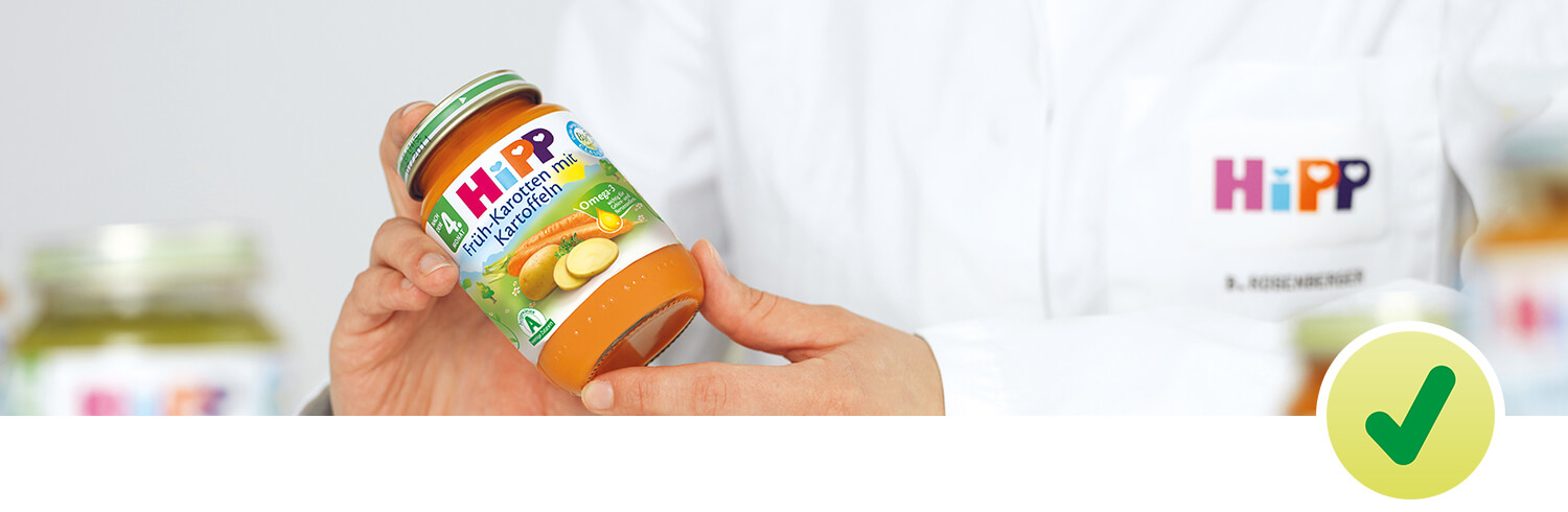 A person in a white lab coat is holding a jar of baby food with a green checkmark symbol.
