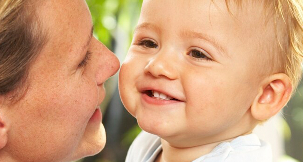 A close-up of a woman and a baby, with the woman's face close to the baby's, capturing a tender moment.