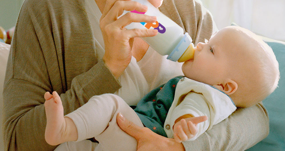 A woman feeds a baby with a bottle.