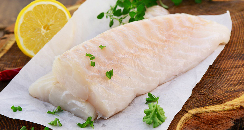 A fresh fish fillet garnished with parsley and lemon slices.