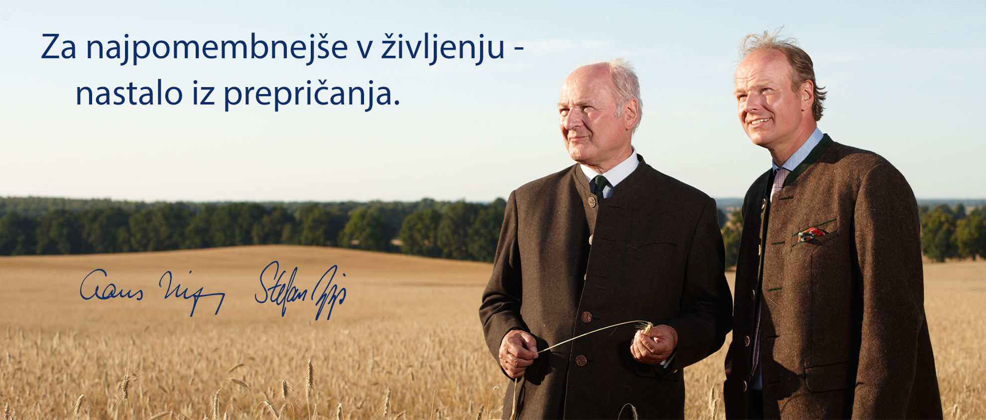 Dva moška v oblekah stojita na pšeničnem polju in imata citat v tujem jeziku.