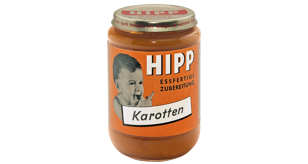 Kozarec otroške hrane Hipp z etiketo, na kateri je upodobljen dojenček, ki jé, in napisom "Karotten", ki označuje okus korenčka.
