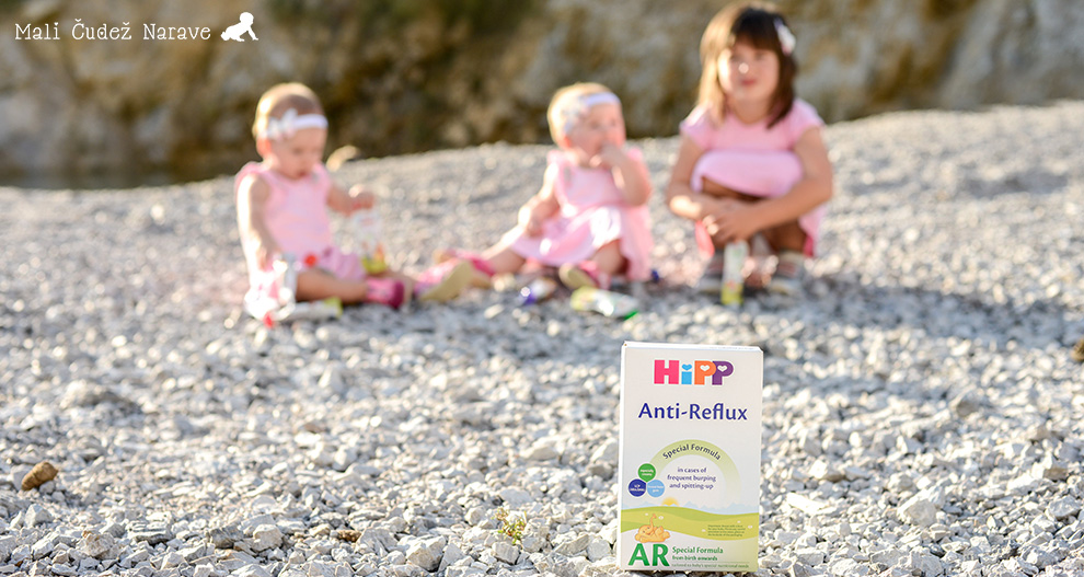 Trije otroci sedijo na skalnati površini, v ospredju pa je škatla z izdelki HiPP Anti-Reflux.