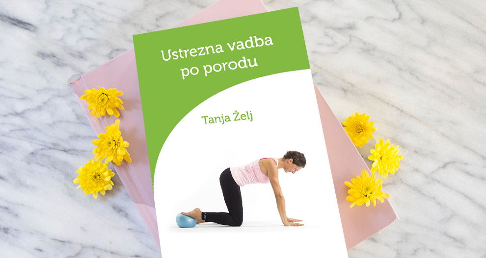 Ženska v roza majici in črnih gatah izvaja jogijski položaj z modro vadbeno žogo na zeleno-beli knjižni platnici z naslovom Ustrezna vadba po porodu avtorice Tanje Želj, postavljeni na marmorno površino z rumenimi cvetovi.